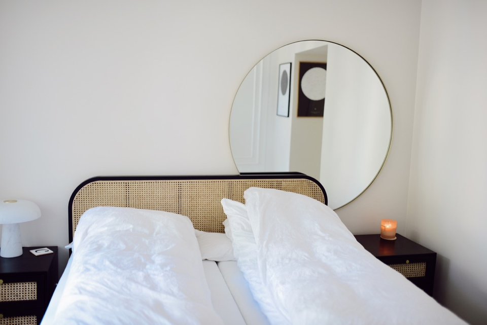 beżowa sypialnia okrągłe lustro ratanowe czarne łóżko inspiracje - 1
